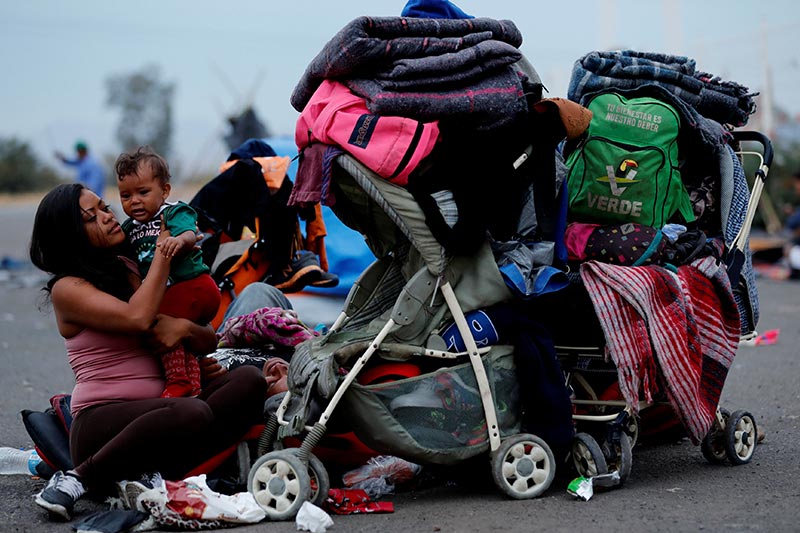 Una migrante hondureña se ocupa de su bebé, mientras espera el bus para ir a Tijuana. © Reuters